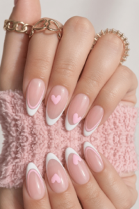Long glossy pink almond-shaped nails with delicate white flowers, gold accents, and sparkling rhinestones.