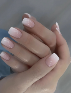 Short square-shaped nude pink nails with glossy finish and delicate white French tips.